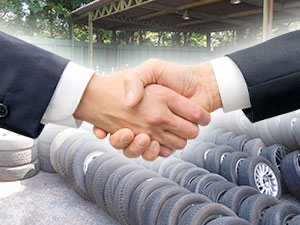 タイヤの前で握手をする写真